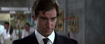 Movie still from “The Living Daylights” (1987), directed by John Glen – A person wearing a suit and tie; Close Up shot, Over the shoulder angle