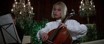 Movie still from “The Living Daylights” (1987), directed by John Glen – A woman in a white shirt playing a cello; Medium shot, Low angle