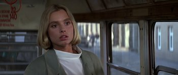 Movie still from “The Living Daylights” (1987), directed by John Glen – A woman with blonde hair is standing on a bus; Close Up shot, Over the shoulder angle