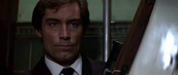 Movie still from “The Living Daylights” (1987), directed by John Glen – A man in a suit and tie holding a gun; Close Up shot, Low angle