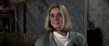 Movie still from “The Living Daylights” (1987), directed by John Glen – A woman with blonde hair sitting on a couch; Close Up shot, Over the shoulder angle