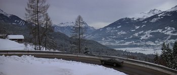 Movie still from “The Living Daylights” (1987), directed by John Glen – A car driving down a road in the snow; Extreme Wide shot, High angle