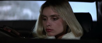 Movie still from “The Living Daylights” (1987), directed by John Glen – A woman sitting in front of a window looking sad; Close Up shot, High angle