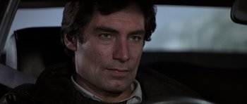 Movie still from “The Living Daylights” (1987), directed by John Glen – Close up of a man in a car looking at the camera; Close Up shot, Over the shoulder angle
