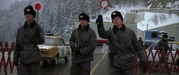 Movie still from “The Living Daylights” (1987), directed by John Glen – A couple of men standing next to each other on a street; Medium shot, Low angle