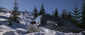 Movie still from “The Living Daylights” (1987), directed by John Glen – A car that is stuck in the snow on the side of a hill; Extreme Wide shot, Low angle