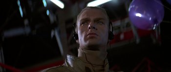 Movie still from “The Living Daylights” (1987), directed by John Glen – A man wearing headphones looking up at the ceiling; Close Up shot, Low angle