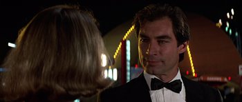 Movie still from “The Living Daylights” (1987), directed by John Glen – A man in a tuxedo talking to a woman in a black dress; Close Up shot, Over the shoulder angle