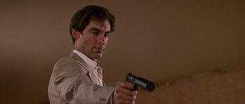Movie still from “The Living Daylights” (1987), directed by John Glen – A man in a suit holding a gun in his hand; Close Up shot, Low angle