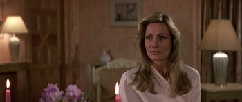 Movie still from “The Living Daylights” (1987), directed by John Glen – A woman sitting in front of a candle in a living room; Close Up shot, Over the shoulder angle