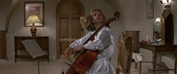 Movie still from “The Living Daylights” (1987), directed by John Glen – A woman in a white dress holding a cello; Medium shot, Low angle