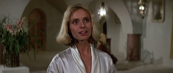 Movie still from “The Living Daylights” (1987), directed by John Glen – A woman with blonde hair wearing a white robe; Close Up shot, Low angle