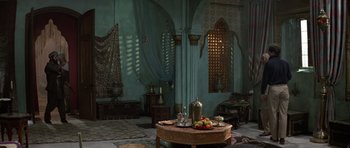 Movie still from “The Living Daylights” (1987), directed by John Glen – A table with a bowl of fruit on top of it in a room; Extreme Wide shot, High angle