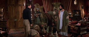 Movie still from “The Living Daylights” (1987), directed by John Glen – A group of men standing around a table; Wide shot, Over the shoulder angle