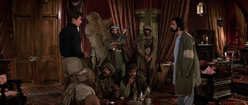 Movie still from “The Living Daylights” (1987), directed by John Glen – A group of men sitting around a table; Wide shot, Over the shoulder angle