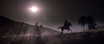 Movie still from “The Living Daylights” (1987), directed by John Glen – Two people on horseback riding through the desert; Extreme Wide shot, Low angle
