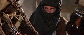 Movie still from “The Living Daylights” (1987), directed by John Glen – A man with a black head covering looking into the camera; Close Up shot, Over the shoulder angle