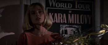 Movie still from “The Living Daylights” (1987), directed by John Glen – A woman in a red dress is holding a tray of food; Close Up shot, Low angle