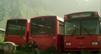Movie still from “The Loneliest Planet” (2011), directed by Julia Loktev – Three red buses are parked in a field; Wide shot, Low angle