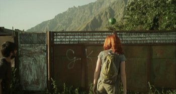 Movie still from “The Loneliest Planet” (2011), directed by Julia Loktev – A woman with a backpack standing in front of a fence; Wide shot, Low angle