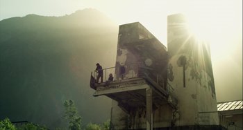 Movie still from “The Loneliest Planet” (2011), directed by Julia Loktev – A person standing on top of a building near trees; Extreme Wide shot, Low angle
