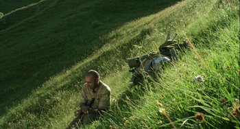 Movie still from “The Loneliest Planet” (2011), directed by Julia Loktev – A man sitting in the grass with a backpack; Wide shot, Low angle
