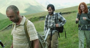 Movie still from “The Loneliest Planet” (2011), directed by Julia Loktev – A man in a plaid shirt is walking in the grass; Medium shot, Low angle
