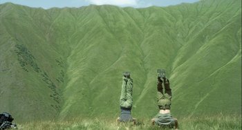Movie still from “The Loneliest Planet” (2011), directed by Julia Loktev – Two people are doing a handstand in the grass; Wide shot, Low angle
