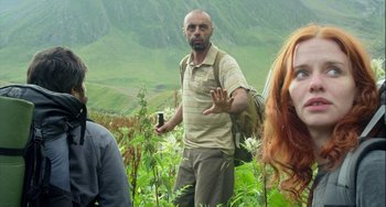 Movie still from “The Loneliest Planet” (2011), directed by Julia Loktev – A man with a beard is standing in a field; Medium shot, Low angle