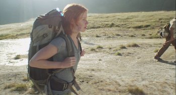 Movie still from “The Loneliest Planet” (2011), directed by Julia Loktev – A woman with a backpack walking through a field; Medium shot, Low angle