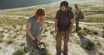 Movie still from “The Loneliest Planet” (2011), directed by Julia Loktev – A woman and a man in a field with a backpack; Wide shot, Low angle