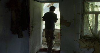 Movie still from “The Loneliest Planet” (2011), directed by Julia Loktev – A man standing in a doorway looking out a window; Wide shot, Low angle