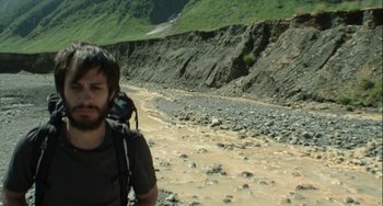 Movie still from “The Loneliest Planet” (2011), directed by Julia Loktev – A man with a camera walking along the side of a road; Medium shot, High angle