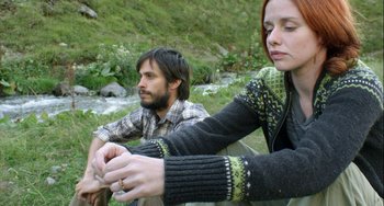 Movie still from “The Loneliest Planet” (2011), directed by Julia Loktev – A man and a woman sitting next to each other on the grass; Medium shot, High angle