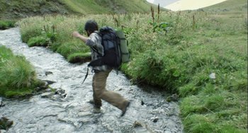 Movie still from “The Loneliest Planet” (2011), directed by Julia Loktev – A man with a backpack walking across a stream; Wide shot, High angle