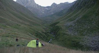 Movie still from “The Loneliest Planet” (2011), directed by Julia Loktev – A person standing next to a tent in the mountains; Extreme Wide shot, High angle