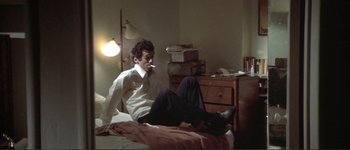 Movie still from “The Long Goodbye” (1973), directed by Robert Altman – A man sitting on a bed in a room; Medium shot, High angle