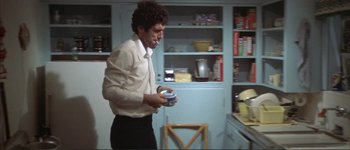 Movie still from “The Long Goodbye” (1973), directed by Robert Altman – A man in a white shirt is holding a can; Medium shot, Low angle