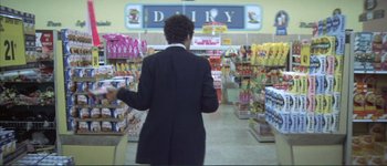 Movie still from “The Long Goodbye” (1973), directed by Robert Altman – A man in a black suit is walking through a store; Wide shot, Low angle