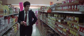 Movie still from “The Long Goodbye” (1973), directed by Robert Altman – A man in a suit and tie standing in a store; Medium shot, Low angle