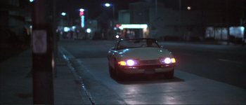 Movie still from “The Long Goodbye” (1973), directed by Robert Altman – A car is driving down the street at night; Wide shot, Low angle
