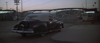 Movie still from “The Long Goodbye” (1973), directed by Robert Altman – An old car driving down a street at night; Wide shot, Low angle