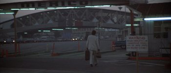 Movie still from “The Long Goodbye” (1973), directed by Robert Altman – A woman walking down a street holding a suitcase; Wide shot, Low angle