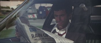 Movie still from “The Long Goodbye” (1973), directed by Robert Altman – A man sitting in the back seat of a car while reading a newspaper; Close Up shot, Low angle