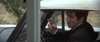 Movie still from “The Long Goodbye” (1973), directed by Robert Altman – A man sitting in the driver's seat of a car; Close Up shot, Over the shoulder angle