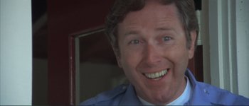 Movie still from “The Long Goodbye” (1973), directed by Robert Altman – A man smiling for the camera; Close Up shot, Low angle