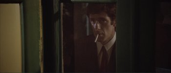 Movie still from “The Long Goodbye” (1973), directed by Robert Altman – A man smoking a cigarette while looking out of a window; Close Up shot, Low angle