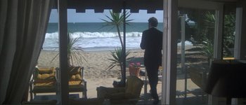 Movie still from “The Long Goodbye” (1973), directed by Robert Altman – A man in a suit standing in front of the ocean; Wide shot, High angle