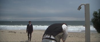 Movie still from “The Long Goodbye” (1973), directed by Robert Altman – Two men on the beach one is taking a picture; Wide shot, Low angle