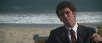 Movie still from “The Long Goodbye” (1973), directed by Robert Altman – A man in a suit sitting on a chair on the beach; Close Up shot, Low angle